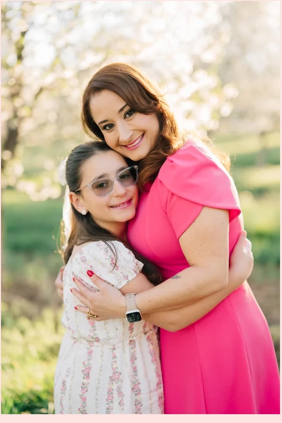 Thaís Marina embracing her daughter in a blooming orchard